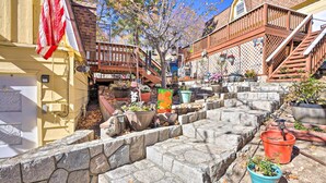 Ein schmaler Steinweg, gesäumt von Topfpflanzen, mit einer hölzernen Treppe zu einer Terrasse.