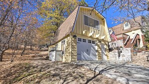 Ein zweistöckiges Haus mit Garage, umgeben von Bäumen und einer Steintreppe, die zum Eingang führt.