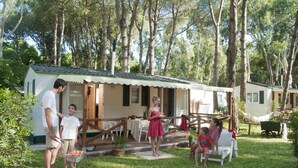 A family dining outdoors in a cottage-style setting with a covered patio and a garden.