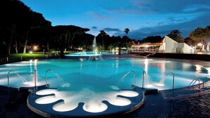 A circular pool with a central fountain, surrounded by a paved area with steps leading to a covered seating area. - Relaxing Stay by the Sea (Baia Domizia (CE))