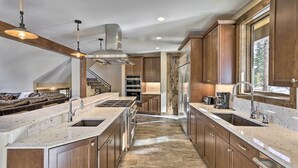 A modern kitchen with wooden cabinets, a central island, stainless steel appliances, and a stone backsplash. - 3 Fireplaces & Mtn View: Luxe Home in Breckenridge (Breckeridge)