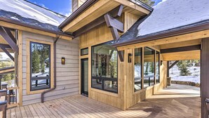 A wooden deck with large windows, a covered area, and a view of snow-covered trees. - 3 Fireplaces & Mtn View: Luxe Home in Breckenridge (Breckeridge)