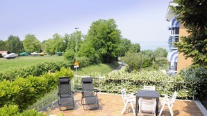 A patio with outdoor seating, a view of the sea, and a garden. - Holiday Home by Lake Garda with Garden (Lazise)