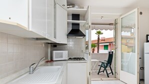 A compact kitchen with a sink, microwave, stove, and cabinets.
