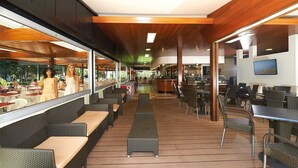 Un restaurant moderne doté d’une terrasse, d’un bar et de grandes fenêtres offrant une vue sur l’extérieur.