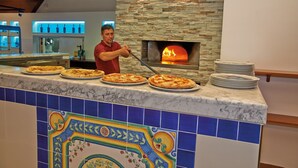 A pizza oven with a man tending to pizzas. - Chalet in Baia Domizia with Private Beach (Baia Domizia (CE))