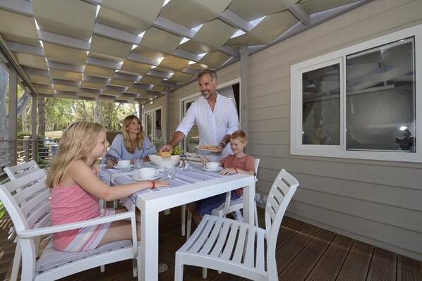 Un espace extérieur abrité, aménagé pour les repas, avec une table dressée pour quatre personnes.