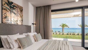 Un dormitorio con una cama grande, vistas al océano y un cuadro con motivos tropicales en la pared.