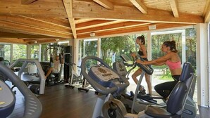 A gym with exercise equipment, large windows, and a wooden ceiling. - Serene Stay by the Shore (Baia Domizia (CE))