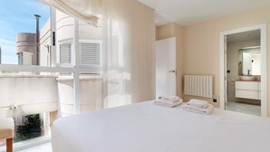 A bedroom with a large bed, a radiator, a bathroom with a sink and mirror, and a view of the outside.