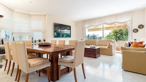 A spacious living area with a dining table, sofas, and a TV.