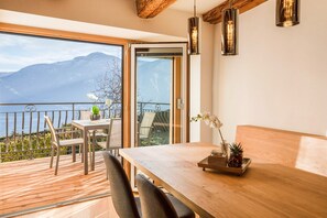 Un balcón con una mesa y sillas de madera, una planta en maceta y vistas a las montañas.