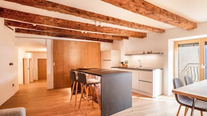 Une cuisine moderne avec des poutres en bois, un îlot central, des tabourets de bar et une table à manger.