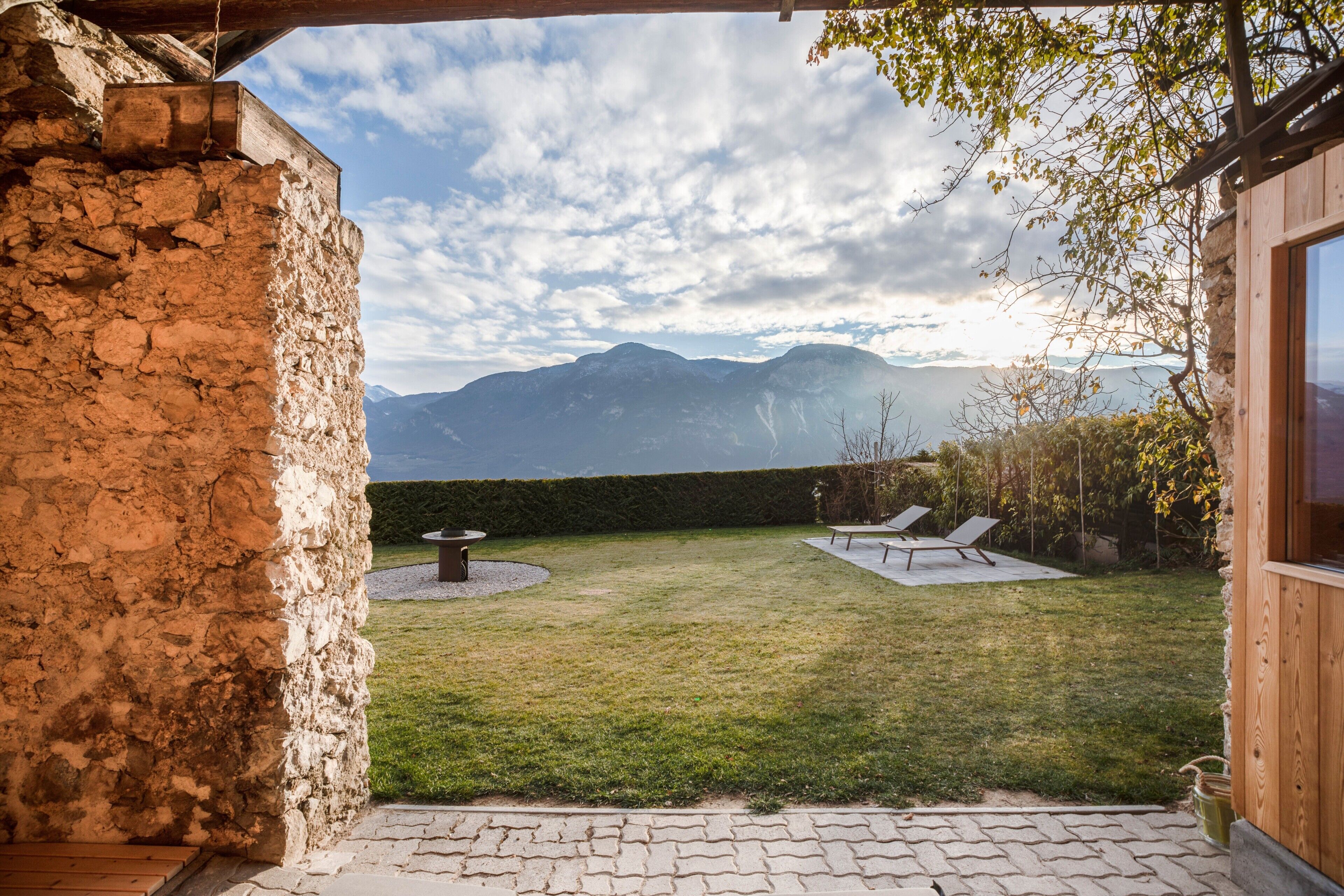 A stone building with a patio, a grassy yard, and a mountain view.