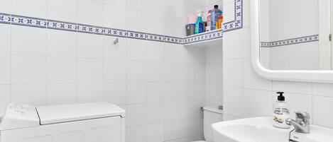 Ein Badezimmer mit Toilette, Waschbecken und einer Waschmaschine.