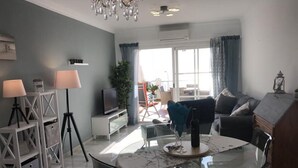 Un soggiorno moderno con un tavolo da pranzo in vetro, un divano, una televisione e un lampadario.