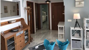 Una stanza con un armadio in legno, un lampadario, un tavolo bianco e una lampada.