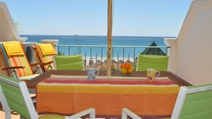 Un balcone con tavolo, sedie e vista sulla spiaggia.