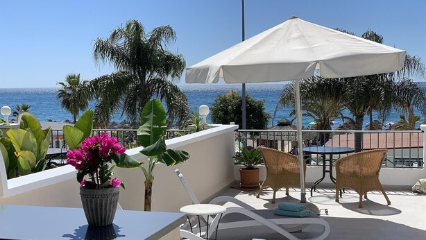 A balcony with a white umbrella, lounge chairs, a table, and potted plants. - Holiday Apartment 'Wonderful Beach" with Sea View, Wi-Fi, Air Conditioning & Terrace (Nerja)