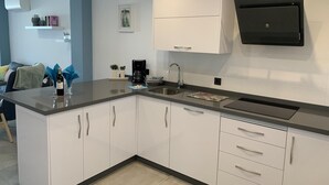A modern kitchen with white cabinets, a black countertop, a coffee maker, and a built-in microwave. - Holiday Apartment 'Wonderful Beach" with Sea View, Wi-Fi, Air Conditioning & Terrace (Nerja)