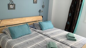 A double bed with striped bedding, two pillows, and a folded towel. - Holiday Apartment 'Wonderful Beach" with Sea View, Wi-Fi, Air Conditioning & Terrace (Nerja)
