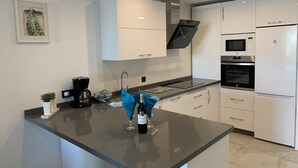 A modern kitchen with white cabinetry, a black countertop, and stainless steel appliances including a refrigerator, oven, and microwave. - Holiday Apartment 'Wonderful Beach" with Sea View, Wi-Fi, Air Conditioning & Terrace (Nerja)