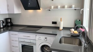 Eine moderne Küche mit Einbauofen, Waschmaschine, Kaffeemaschine und Spüle.