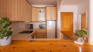 A kitchen with wooden cabinets, a microwave, a refrigerator, and a wooden countertop. - 'Sunny Apartment Front Line Burriana' Near the Beach with Sea View, Wi-Fi, A/C & Balcony (Nerja)