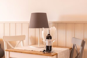 Une table avec une bouteille de vin, deux verres, une lampe et une chaise.
