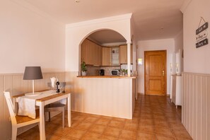 Cozinha com armários de madeira, uma ilha central, micro-ondas e área de jantar com mesa e cadeiras.