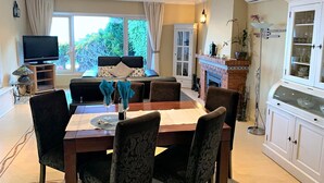 A dining area with a table set for four, a television, and a fireplace. - Wonderful Villa Princessa with Sea & Mountain Views, Pool, and Wi-Fi (Nerja)