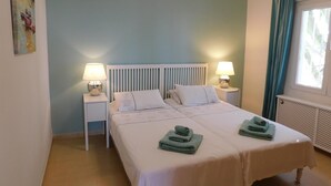 A bedroom with a bed, two bedside tables with lamps, a radiator, and a window with curtains. - Wonderful Villa Princessa with Sea & Mountain Views, Pool, and Wi-Fi (Nerja)