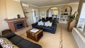 A living room with a fireplace, a sofa set, a coffee table, and a bookshelf. - Wonderful Villa Princessa with Sea & Mountain Views, Pool, and Wi-Fi (Nerja)