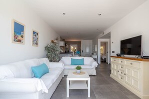 A modern living room with a white sofa, a coffee table, a TV, and a cabinet.