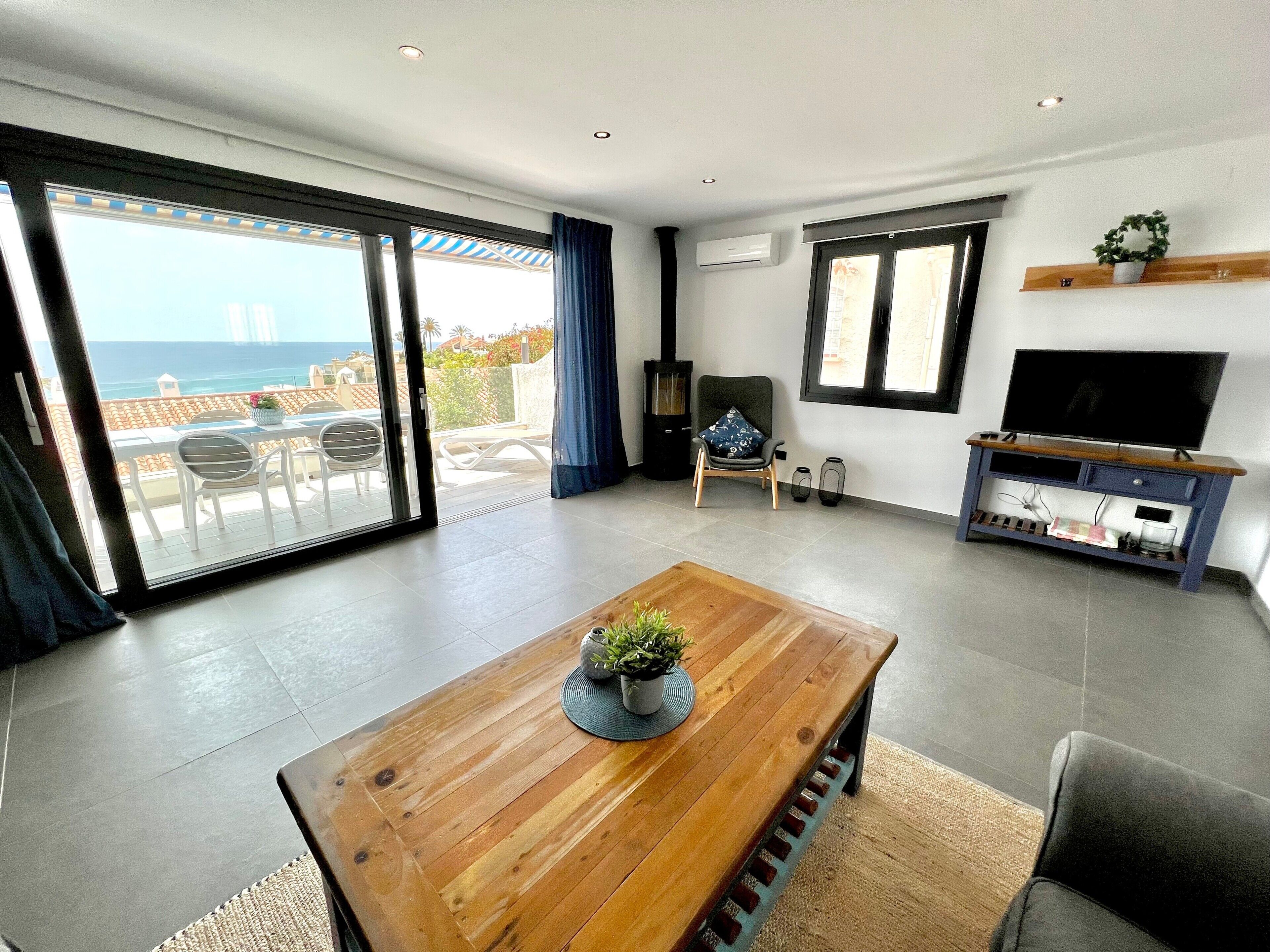 Een moderne woonkamer met een houten salontafel, een tv op een standaard, en een balkon met uitzicht.
