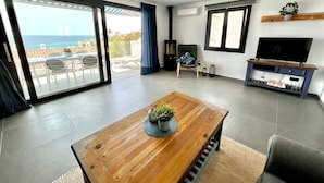 A modern living room with a wooden coffee table, a TV on a stand, and a balcony with a view. - 'Wonderful House by the sea' with Sea & Mountain View, Pool and Wi-Fi (Nerja)