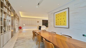Una moderna hall d'albergo con una reception, un grande tavolo in legno e una libreria.