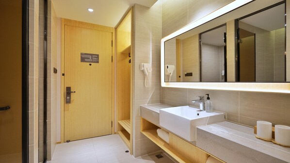 Un bagno moderno con una porta in legno, uno specchio grande, un lavandino bianco e un porta asciugamani.