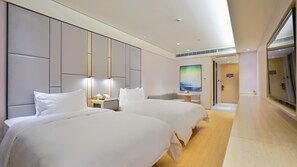 Una camera d'albergo moderna con due letti, un comodino con una lampada, un tavolino con un vaso e un quadro appeso al muro.