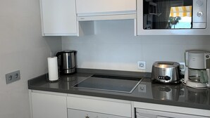 Een moderne keuken met een magnetron, waterkoker, broodrooster en koffiezetapparaat op het aanrecht.