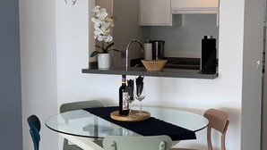 Een moderne keuken met een glazen eettafel, twee stoelen, een potorkidee en een fles wijn.