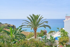 A pool area with a palm tree, a view of the sea, and a building with a balcony. - Wonderful 'Villa Burriana Beach' with Sea View, Pool, Balcony, Terrace & Garden (Nerja)