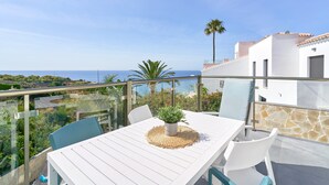 Un balcon avec une table, des chaises et un pot de fleurs.