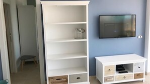 Una stanza con un ripiano bianco, una televisione a muro e un piccolo tavolo.