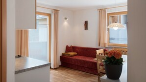 A living room with a sofa, a dining table, and a potted plant. - Apartment "Hilber Furchetta" with Mountain View, Garden and Wi-Fi (Villnöss)