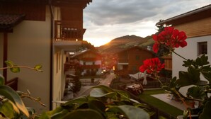 A residential area with houses, a balcony, and a plant with red flowers. - Apartment "Hilber Furchetta" with Mountain View, Garden and Wi-Fi (Villnöss)