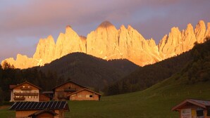 A mountain landscape with a wooden cabin and a smaller building in the foreground. - Apartment "Hilber Furchetta" with Mountain View, Garden and Wi-Fi (Villnöss)