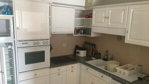 Une cuisine avec des meubles blancs, un lave-vaisselle Bosch, une cuisinière et un évier.