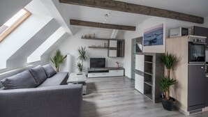 Une cuisine moderne dotée d’appareils électroménagers intégrés, un canapé gris et un coin repas avec une table et des chaises.