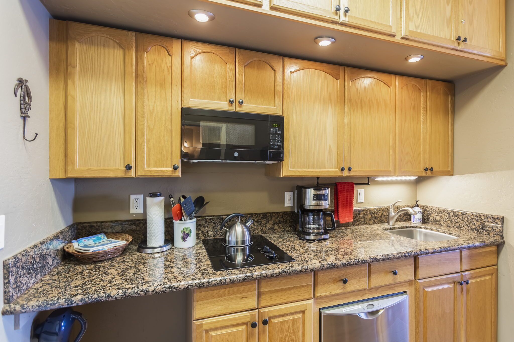 A kitchen with wooden cabinets, a microwave, a coffee maker, and a sink.